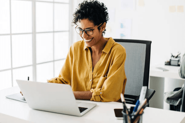 Photo of a relaxed professional working efficiently on a laptop, smiling slightly, with a clean desk